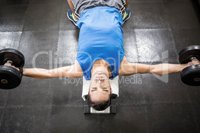 Handsome man lifting dumbbells on bench