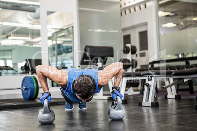 handsome man doing push ups with kettlebells