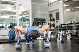 handsome man doing push ups with kettlebells