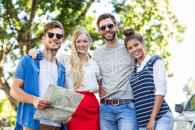 Hip friends holding map and smiling at the camera