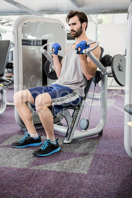 Focused man using weights machine for arms