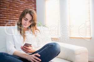 Focused woman sitting on the couch using her phone