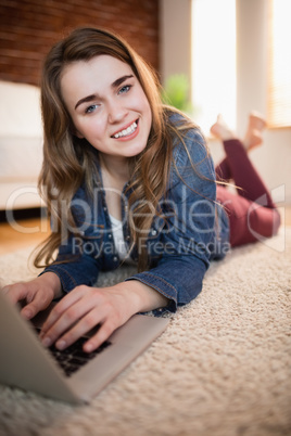 Pretty woman lying on the couch using laptop