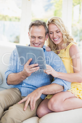 Happy couple using tablet on the sofa