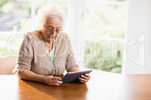 Focused senior woman using tablet