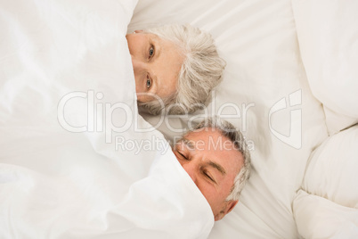 Happy senior couple under duvet in bed