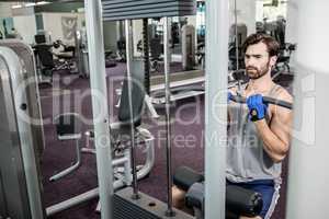 Focused man using weights machine for arms