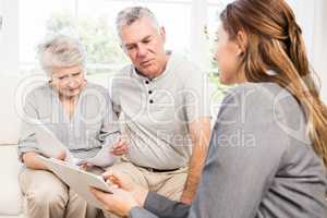 Businesswoman talking with senior couple and showing clipboard