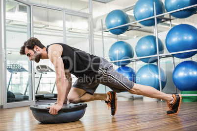 Serious man doing exercise with bosu ball