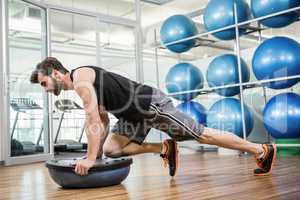 Serious man doing exercise with bosu ball