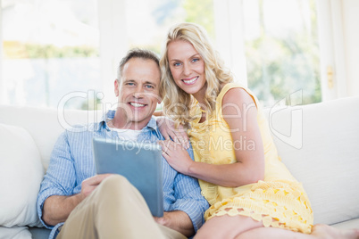 Happy couple using tablet on the sofa