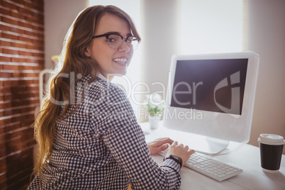 Smiling hipster businesswoman typing on computer
