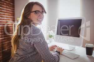 Smiling hipster businesswoman typing on computer