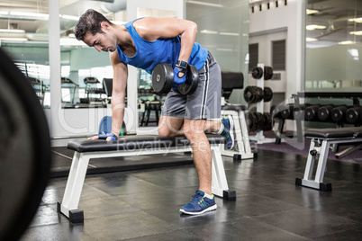 Handsome man lifting dumbbells on bench