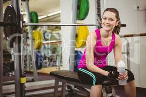 Smiling woman sitting on barbell bench