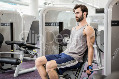 Focused man using weights machine for arms