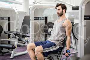 Focused man using weights machine for arms