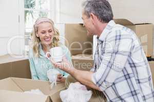 Smiling couple packing mug in a box