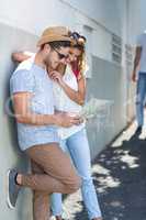 Hip couple checking map and leaning against wall
