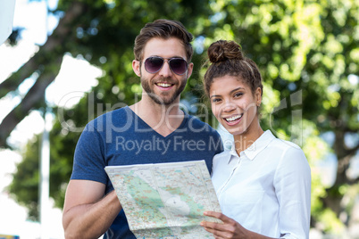 Hip friends holding map and smiling at the camera