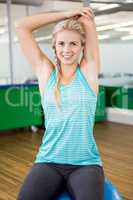 Fit woman stretching and sitting on exercise ball