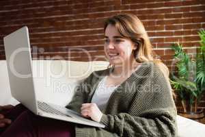 Pretty woman using laptop lying on the couch