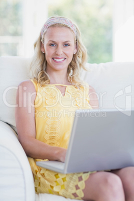 Happy woman using laptop on sofa