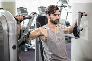 Focused man using weights machine for arms