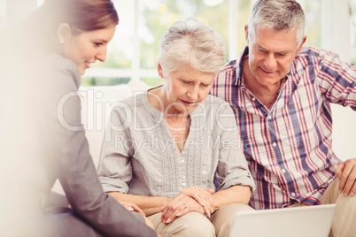 Smiling businesswoman showing laptop monitor to senior couple