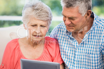 Doubtful senior couple using tablet