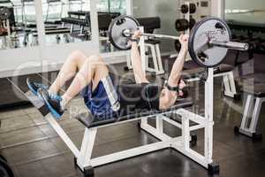 Muscular man lifting barbell on bench