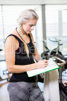 Smiling female trainer writing on clipboard