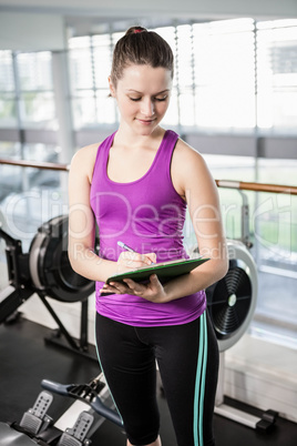 Pretty trainer writing on clipboard