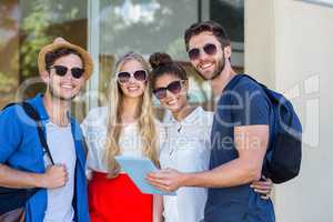 Hip friends holding tablet and smiling at the camera