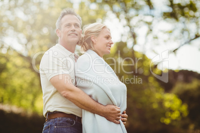 Husband hugging his wife in a blanket