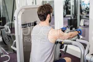 Focused man using weights machine for arms