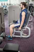 Focused man using weights machine for legs