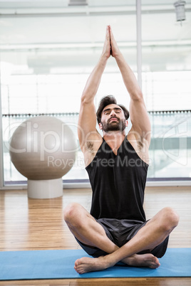 Handsome man doing yoga on mat