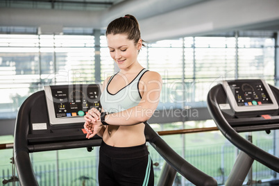 Smiling woman on treadmill using smart watch