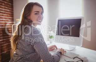 Smiling hipster businesswoman typing on computer