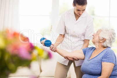 Physiotherapist taking care of sick elderly patient