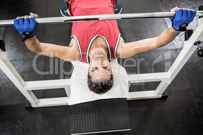 Muscular man lifting barbell on bench