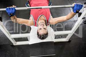 Muscular man lifting barbell on bench