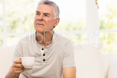 Thoughtful senior man holding mug