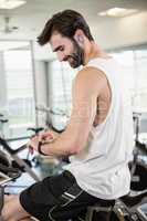 Smiling man on exercise bike using smartwatch