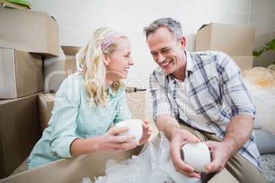 Smiling couple packing mug in a box