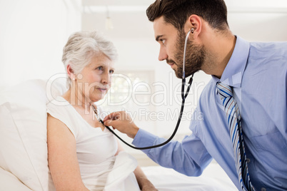 Home nurse listening to chest of patient with stethoscope