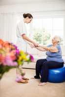 Physiotherapist taking care of sick elderly patient