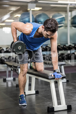 Handsome man lifting dumbbells on bench