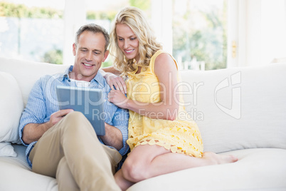 Happy couple using tablet on the sofa